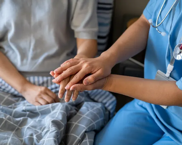 Nurse holding elderly patient hand providing home nursing care in Kuwait